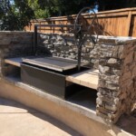 Santa Maria style drop in brick lined firebox built in stacked stone outdoor fireplace kitchen