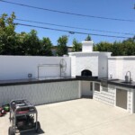 Professional outdoor grill setup with stainless steel appliances and charcoal grill.