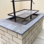 A simple single crank wood fired grill frame insert sets into a masonry opening.