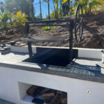 All black iron wood burning grill with adjustable grill grate.